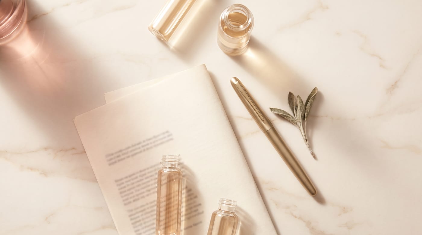 Laborfläschchen, ein Befundblatt, ein goldener Stift und ein Salbeizweig auf hellem Marmor